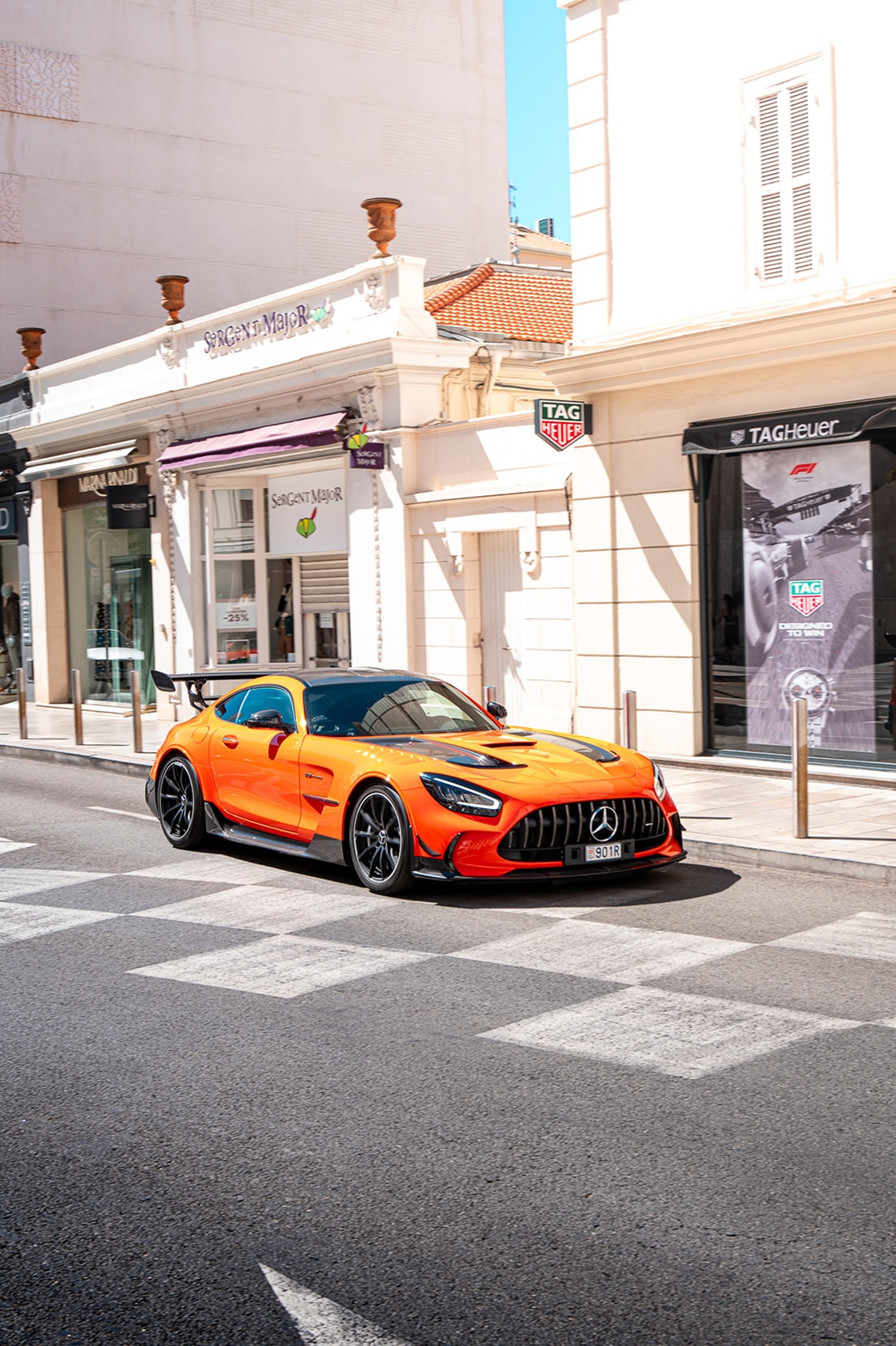 Une Mercedes-AMG GT Black Series orange traversant un passage piéton devant une boutique TAG Heuer.